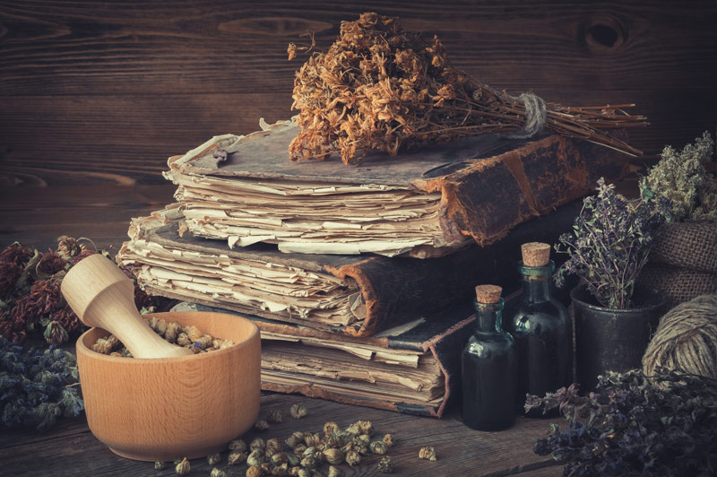 Healing herbs on stacks of old medicine books